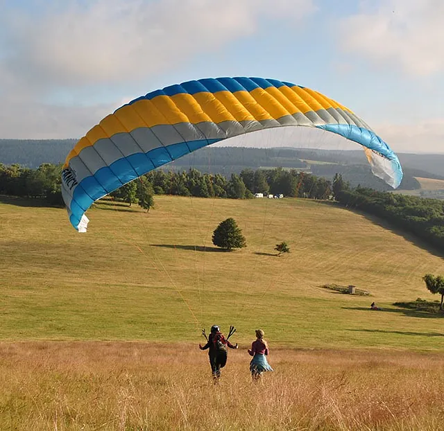 Paraglider zweeft boven het heuvelachtige landschap van het Sauerland.